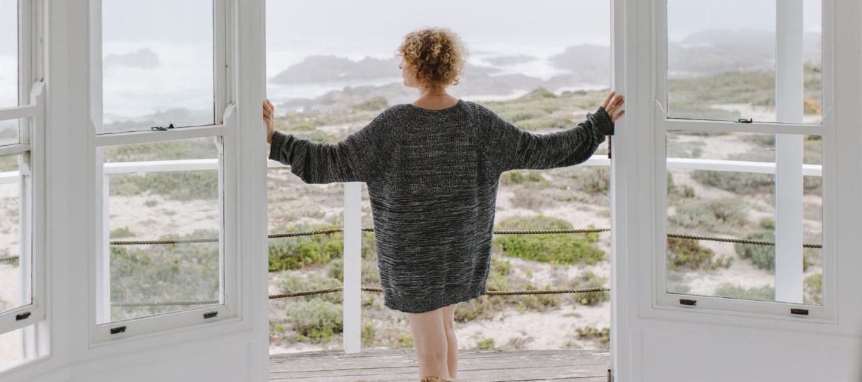 woman at open door looking at the beach landscape