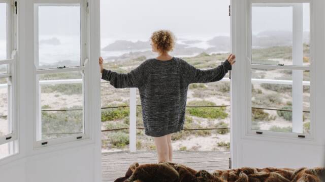 woman at open door looking at the beach landscape