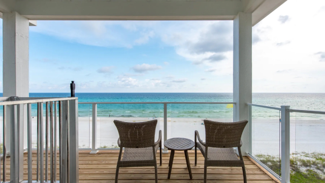 Two chairs and a table on an outdoor deck facing the ocean