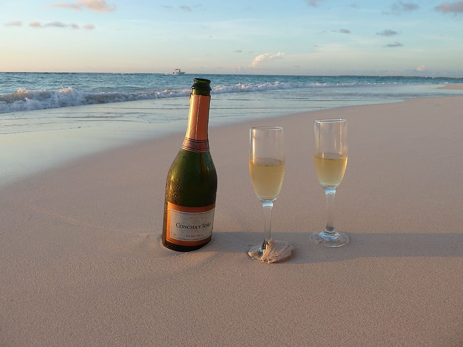 Bottle of Champagne on the sand with 2 glasses