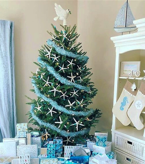 A Christmas tree with blue garland and white starfish as ornaments