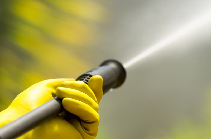 gloved hand holding pressure washer