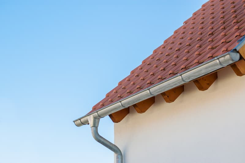 stucco house with terra-cotta roof showing gutters and downspout