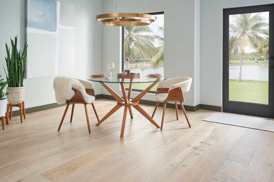 bleached hardwood floors in dining area looking out at ocean waterway with palm trees