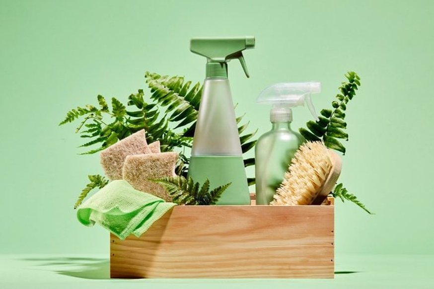 wooden crate full of eco-friendly cleaning supplies and fern leaves