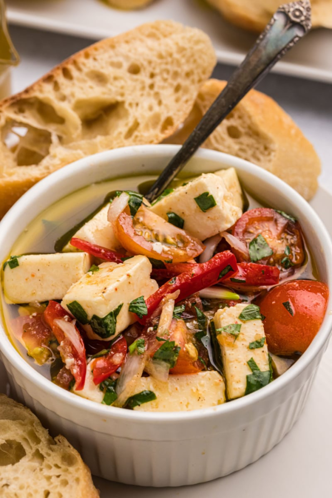 Marinated Cherry Tomatoes with Feta and Fresh Herbs served in white ramekin with French bread in background