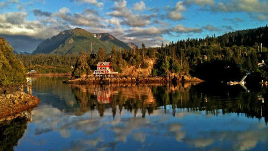 Halibut Cove, Alaska, with mountain scenery in the backdrop and glacier-fed clear waters surrounding the island.