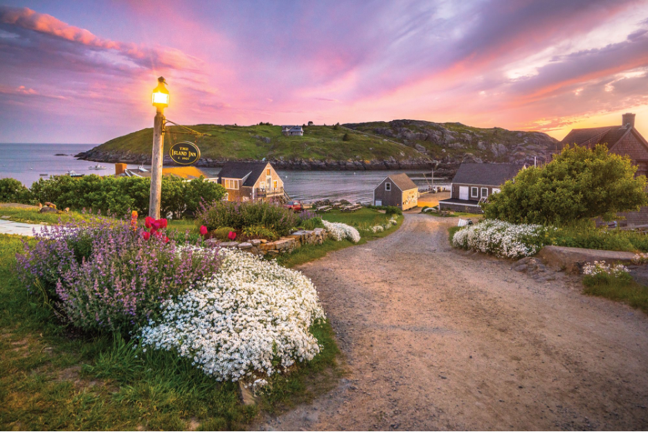 Coastal roadway to The Island Inn, a popular lodge for overnight guests with picturesque hills, houses, and ocean in backdrop