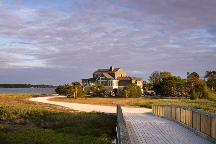 Daufuskie Island scene with boardwalk leading to grand coastal residence with ocean in the backdrop