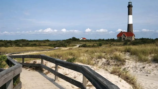 Iconic lighthouse landmark on Fire Island with a boardwalk crossing sand dunes to the beach