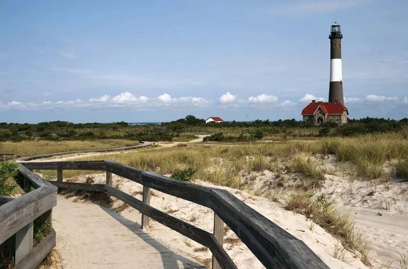 Iconic lighthouse landmark on Fire Island with a boardwalk crossing sand dunes to the beach