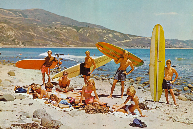 Retro color photo of 1960s surfers on the beach in Santa Barbara, CA, at Rincon with mountains and ocean in backdrop