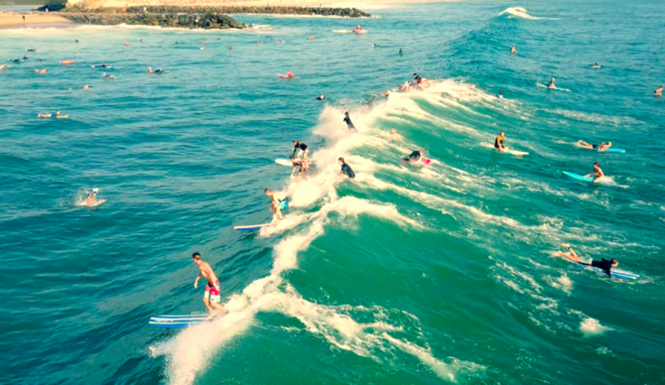 Image of multiple surfers riding the waves in blue turquoise waters