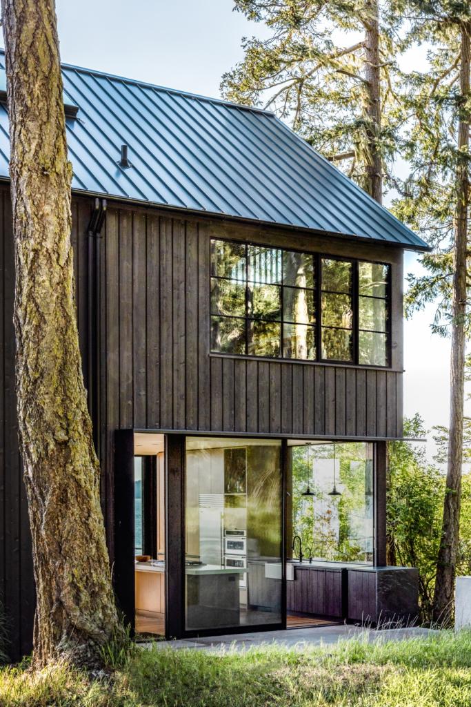 side view of home showing steep gable roof and glazed areas that connect to the outdoors