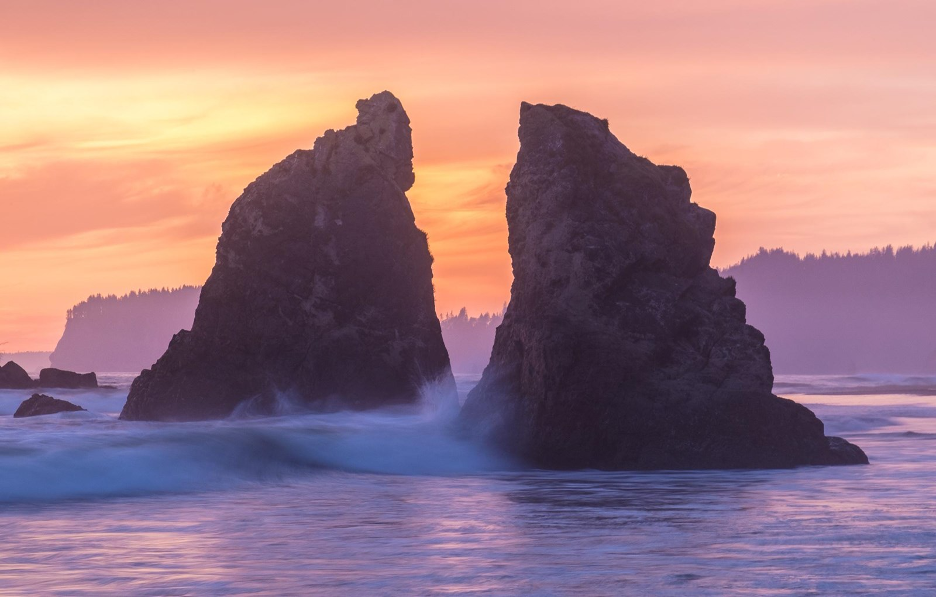 Ruby Beach, Olympic National Park, Washington at sunset with waters crashing around a split seastack and rugged landscape behind