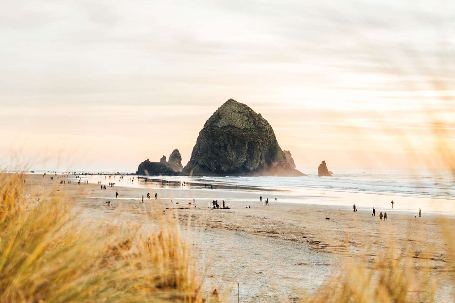 Cannon Beach, Cannon Beach, Oregon with Haystack Rock in background and people combing the beach for sea treasures