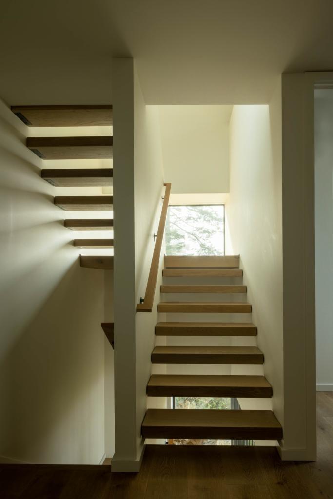 upper-level staircase and landing going to the third-floor loft space with lots of natural light streaming through.