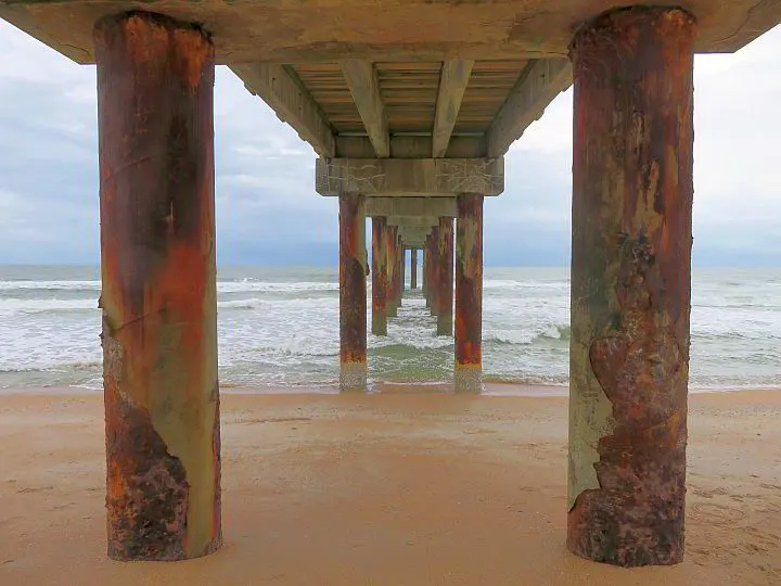 View of the ocean from underneath a fishing pier at St. Augustine Beach in St. Augustine, FL