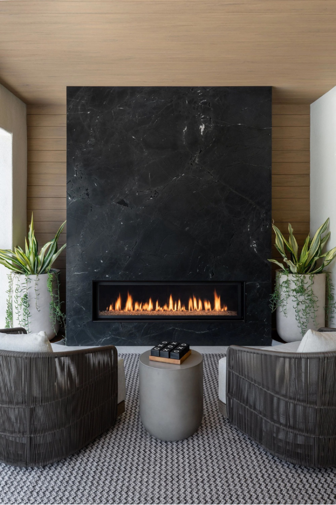Gas Outdoor Fireplace Under a Covered Loggia (California Coast) black stone linear fireplace design with potted plants and outdoor seating