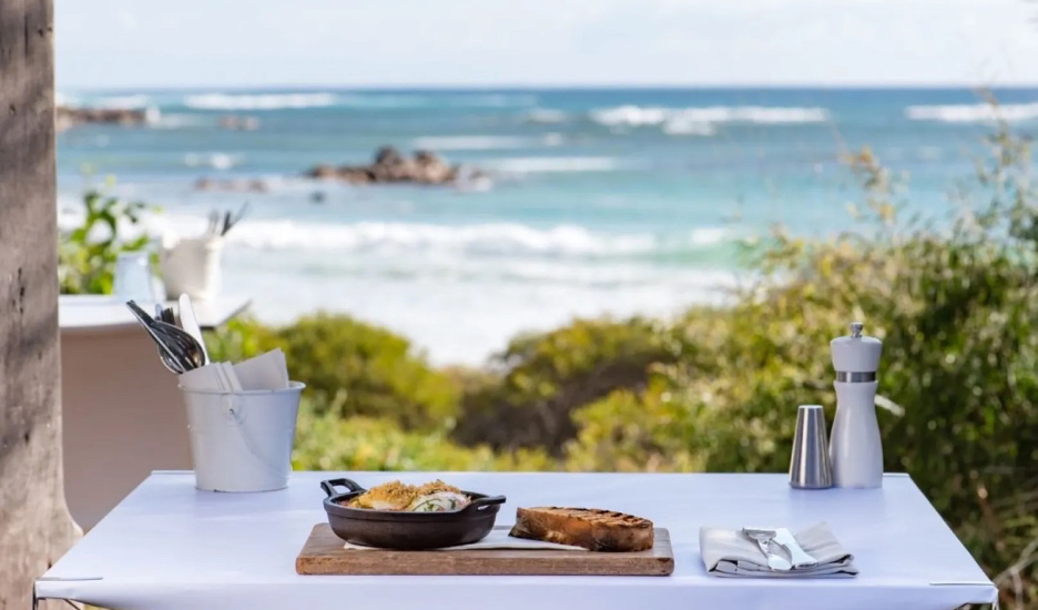 A crisp white al fresco table set for brunch in front of a breathtaking ocean view