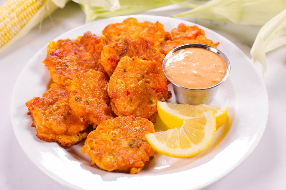 Corn and Lobster Fritters on a white plate with a side of remoulade