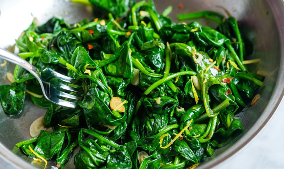 Fresh and vibrant green wilted spinach salad in a bowl with a fork