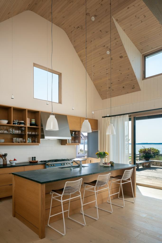 kitchen area with island and views out to the beach via a wall of sliding glass doors. Dark soapstone countertop clads the island.