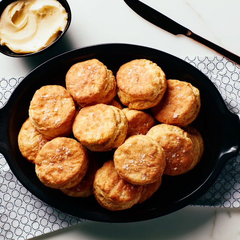 Buttermilk Biscuits with Honey Butter on a black serving dish with bowl of honey butter and knife in the background