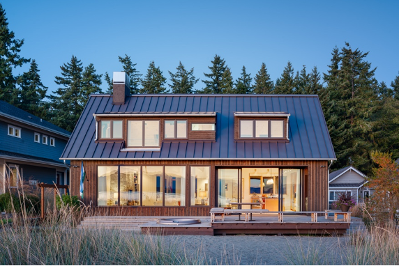 Exterior deck at twilight with hot tub, built-in seating, direct beach access