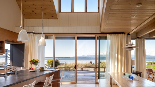 A sweeping view of the Salish Sea and Olympic Mountains from main living space of this beach cabin on Mutiny Bay, Whidbey Island, WA, designed by Seattle firm Graham Baba Architects