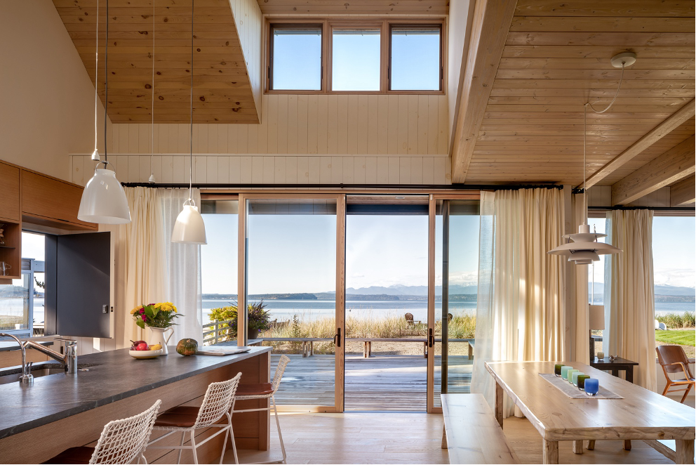 A sweeping view of the Salish Sea and Olympic Mountains from main living space of this beach cabin on Mutiny Bay, Whidbey Island, WA, designed by Seattle firm Graham Baba Architects