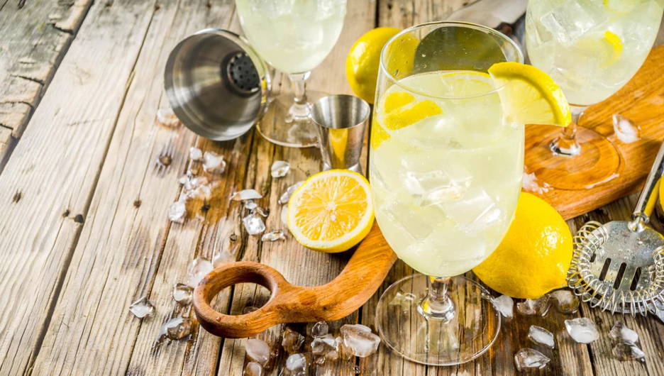 St–Germain cocktails and barware on a rustic wooden table with lemon garnishes
