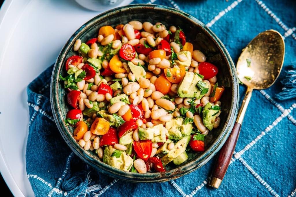 white bean salad in a bowl with blue linen napkin and serving spoon