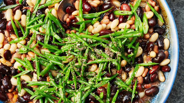 Mixed bean salad in a bowl with serving spoon.