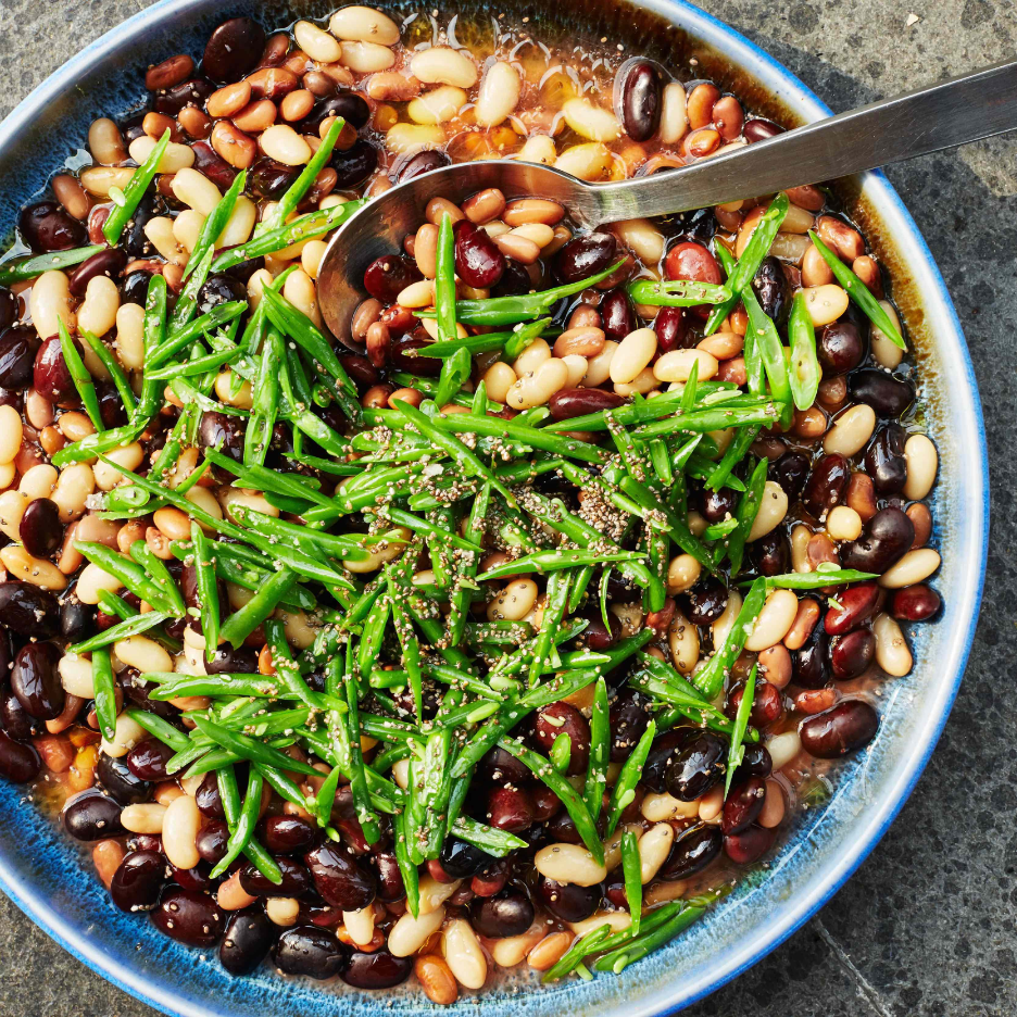 Mixed bean salad in a bowl with serving spoon.